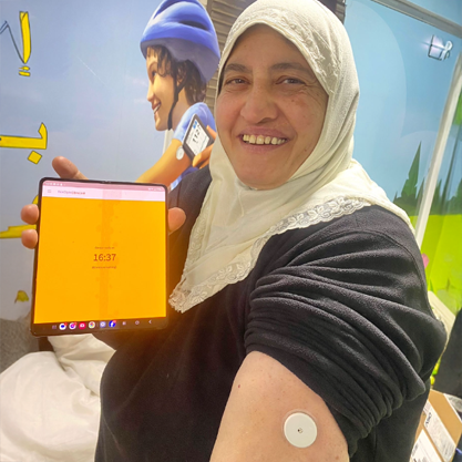 An older woman riding her bike while smiling broadly.