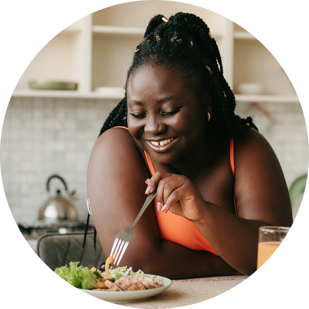 A woman wearing a FreeStyle Libre sensor enjoys a balanced meal of fresh salad and protein at home.