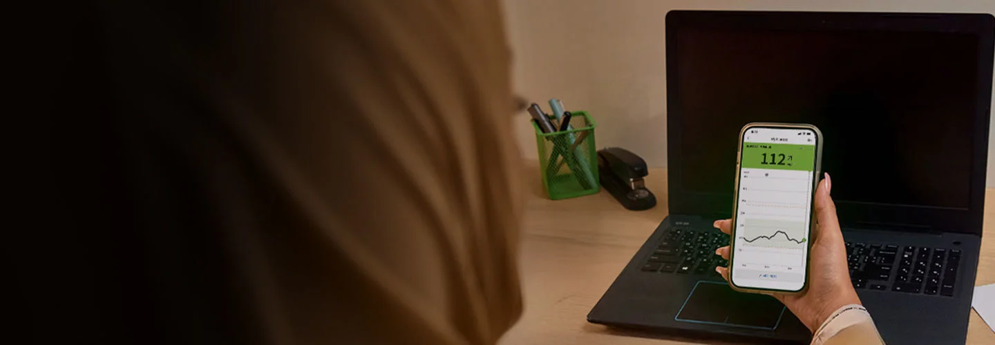 A woman looking at the Abbott  app splash screen on her phone.