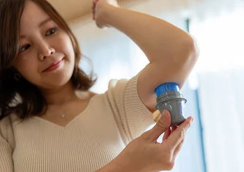  Mujer aplicándose un sensor en el brazo izquierdo.