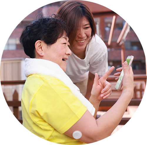 Eine Angehörige und eine Person, die einen FSL-Sensor trägt, überprüfen die Messwerte auf einem Smartphone oder Lesegerät.