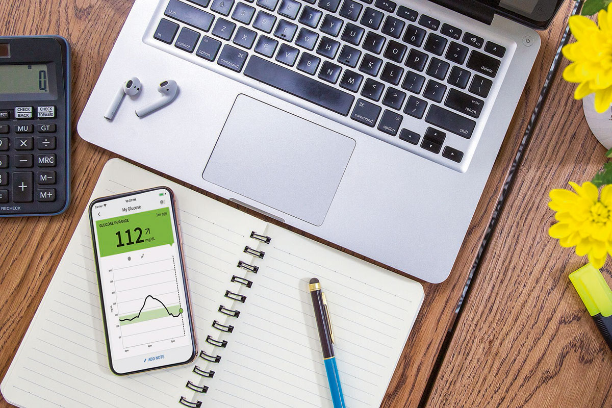 Ein Laptop, ein Smartphone und ein Notizblock mit einem Stift darauf.