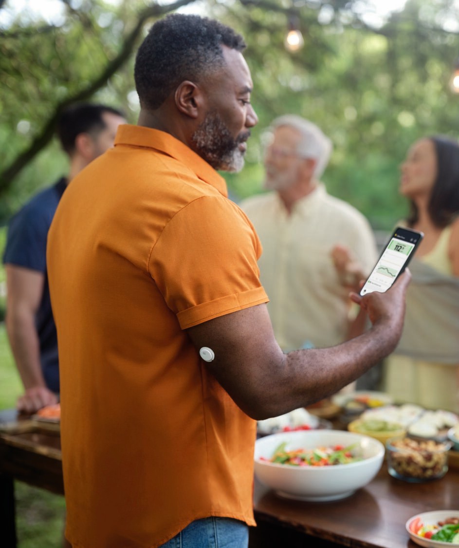 Un homme lors d'un rassemblement avec un capteur sur le bras, consultant son téléphone.