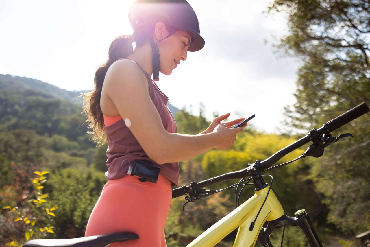 une femme à vélo vérifie sa glycémie sur son téléphone portable