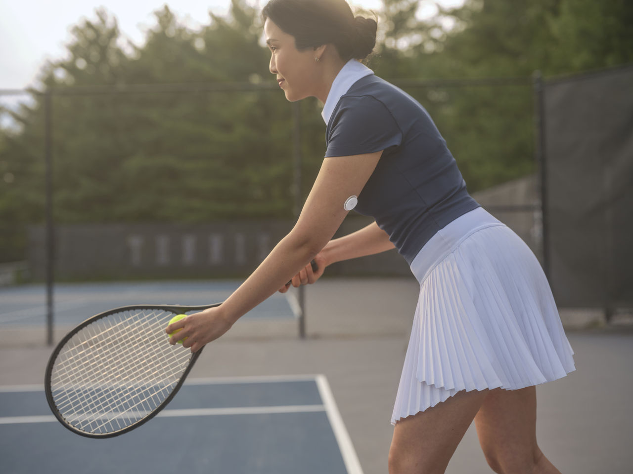 Een vrouw met een sensor op haar bovenarm die tennis speelt.