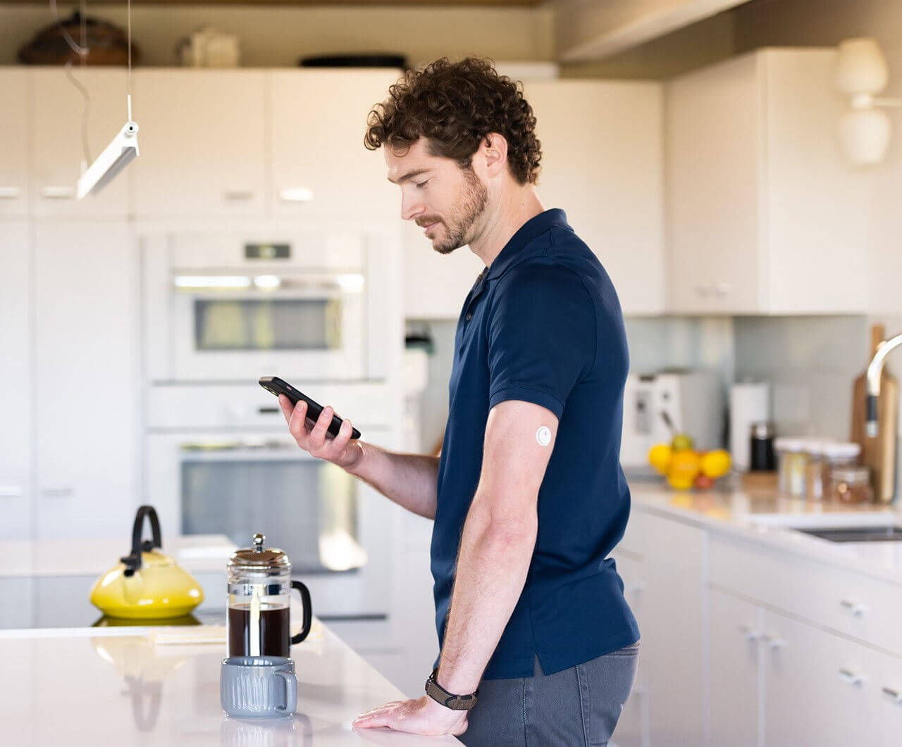 Mann steht in Küche mit Smartphone in der Hand.