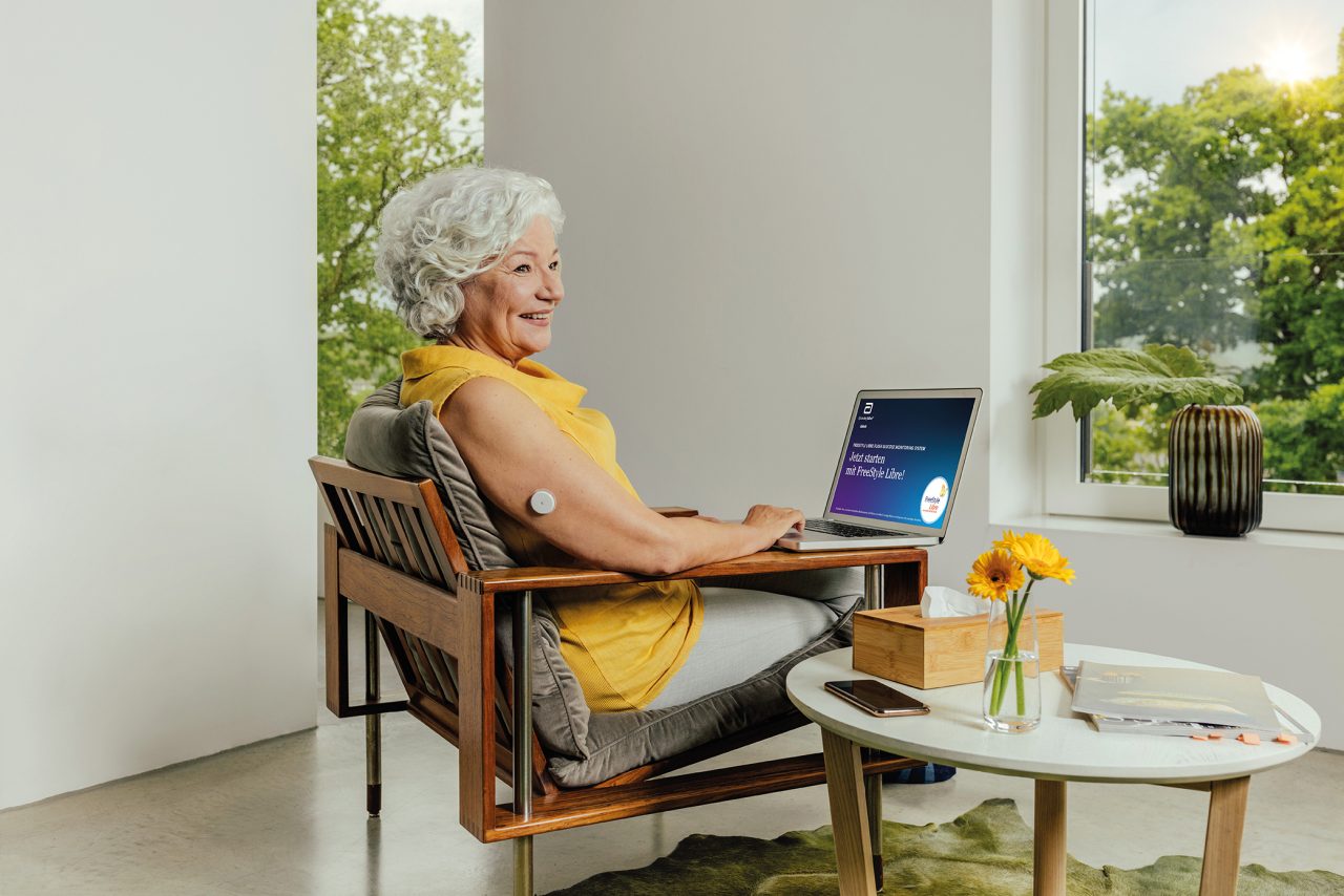 Femme assise devant son ordinateur portable avec le capteur du FreeStyle Libre