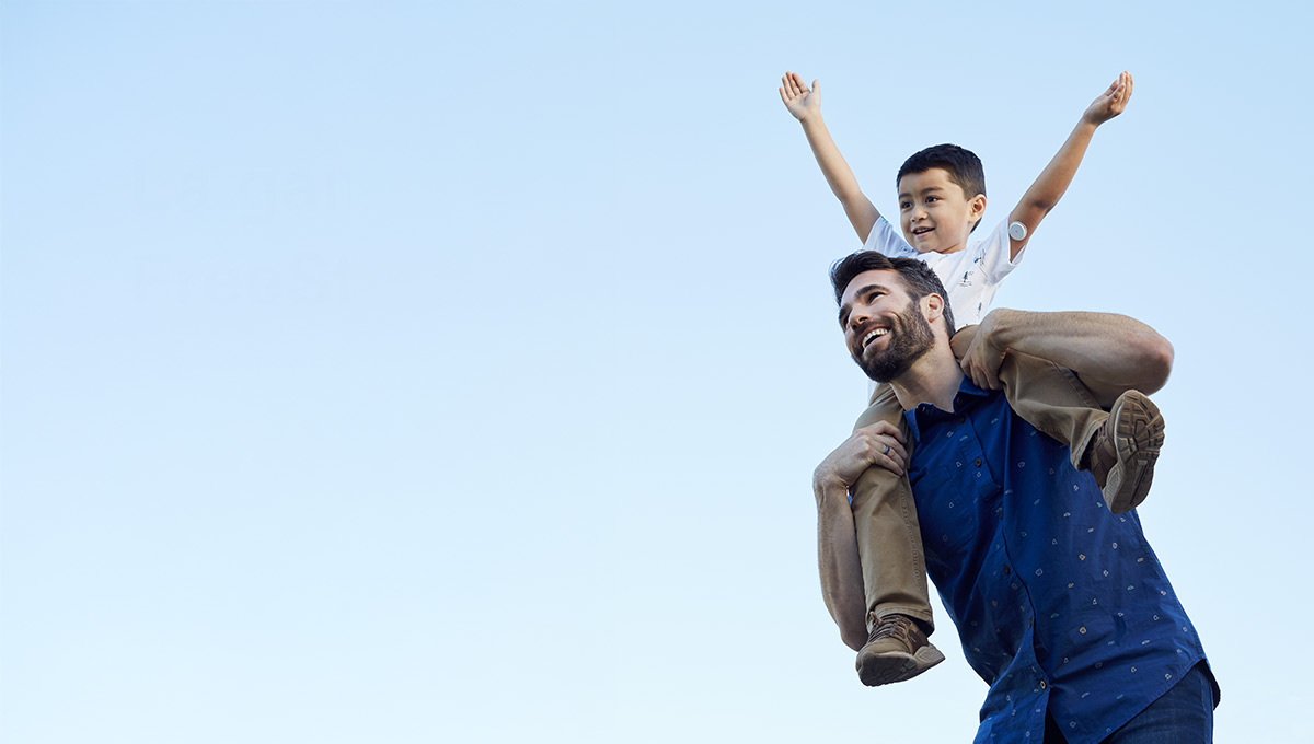 Père et enfant souriants, l’enfant portant un capteur de glucose sur le bras