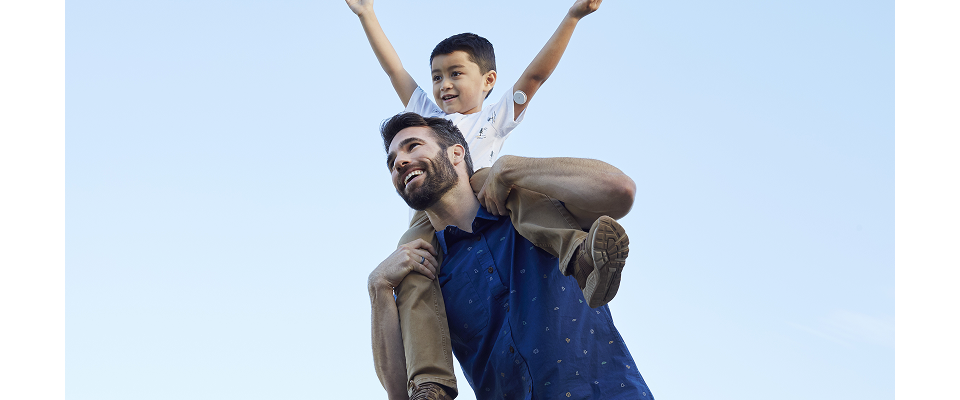 Père et enfant souriants, l’enfant portant un capteur de glucose sur le bras
