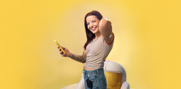 Woman standing by a chair while wearing a FreeStyle Libre 3 Plus sensor