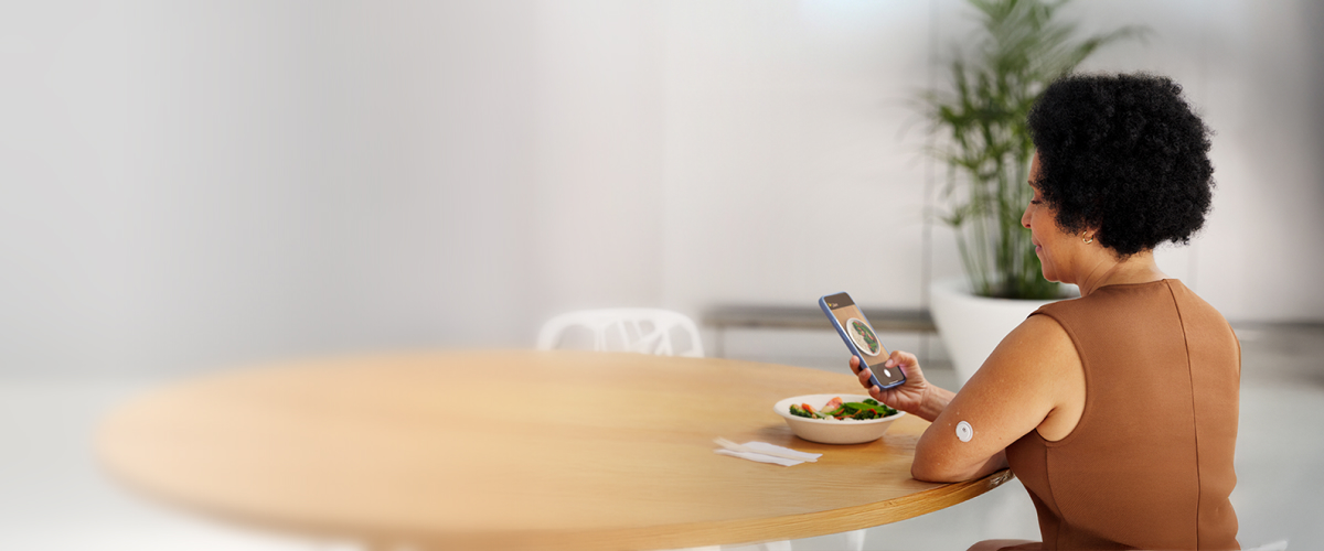 Woman taking a photo of her meal while wearing a FreeStyle Libre 3 Plus sensor