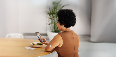 Woman taking a photo of her meal while wearing a FreeStyle Libre 3 Plus sensor