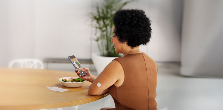 Woman taking a photo of her meal while wearing a FreeStyle Libre 3 Plus sensor