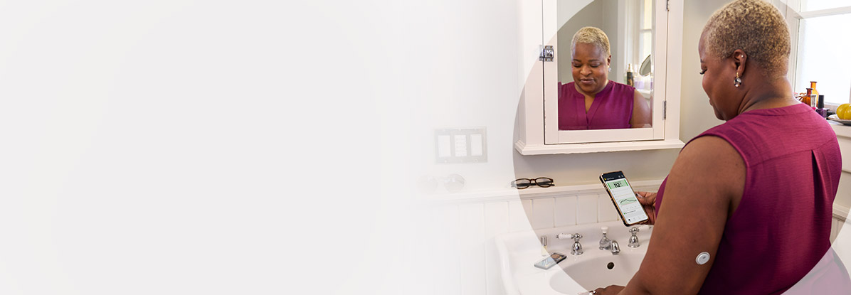 Woman doing her makeup in the mirror while wearing a FreeStyle Libre sensor