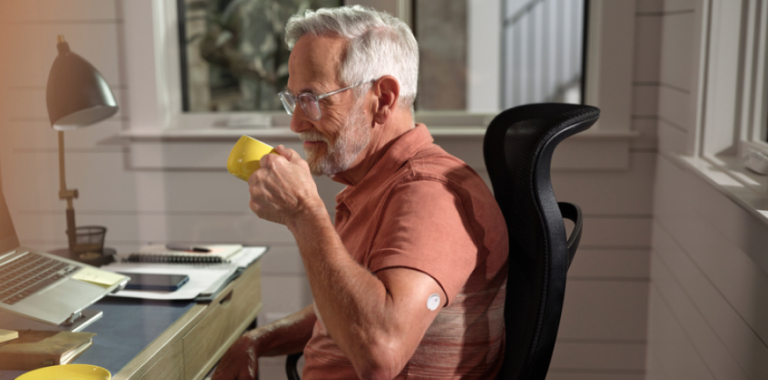 Man drinking coffee while wearing a FreeStyle Libre systems sensor