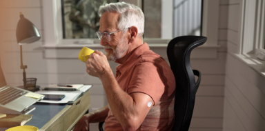 Man drinking coffee while wearing a FreeStyle Libre systems sensor