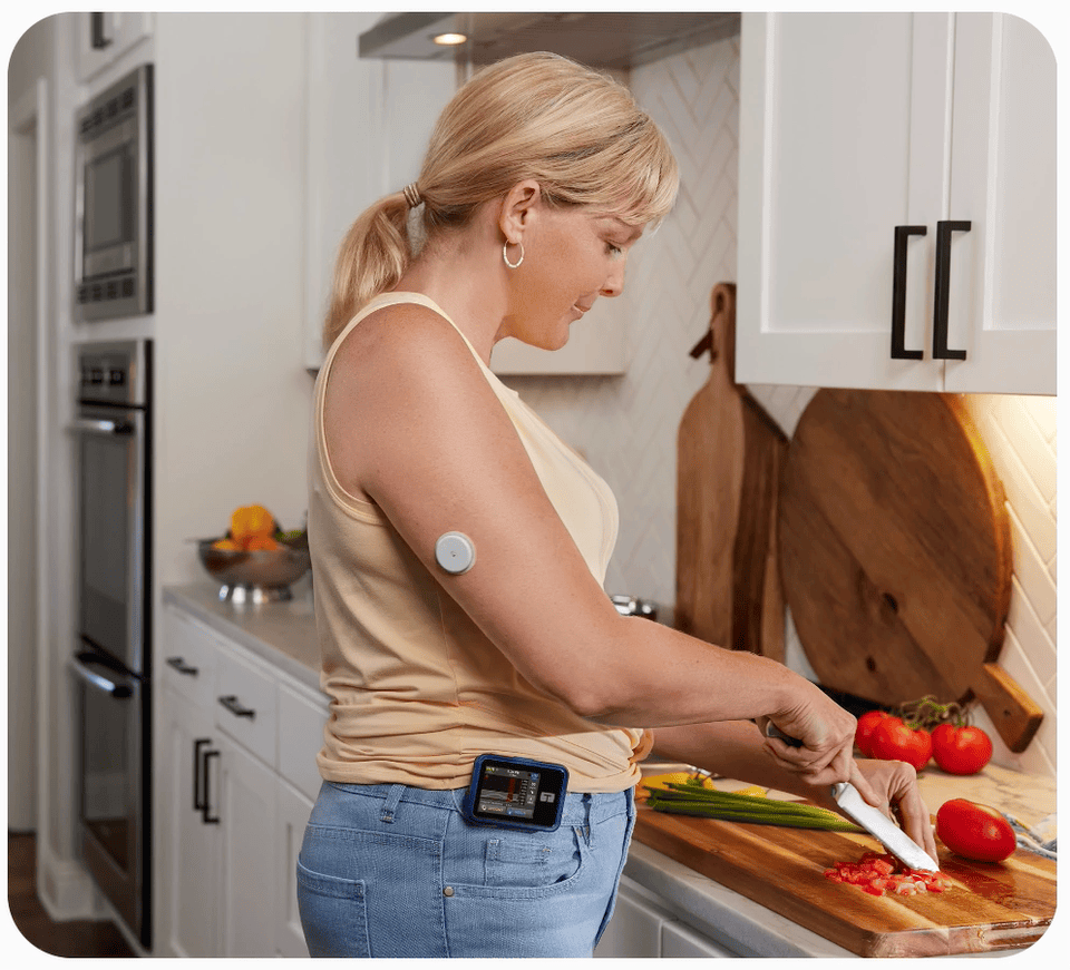 Woman chopping tomatoes while wearing a FreeStyle Libre 2 Plus sensor and a Tandem t:slim X2 insulin pump