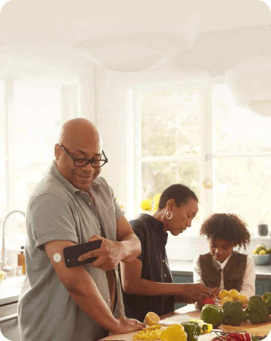 Man testing his blood glucose while cooking in the kitchen with family