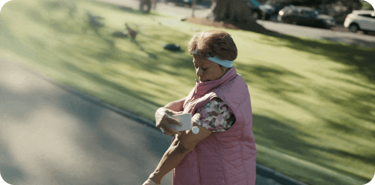 Woman checking her blood glucose on her mobile device while walking a dog
