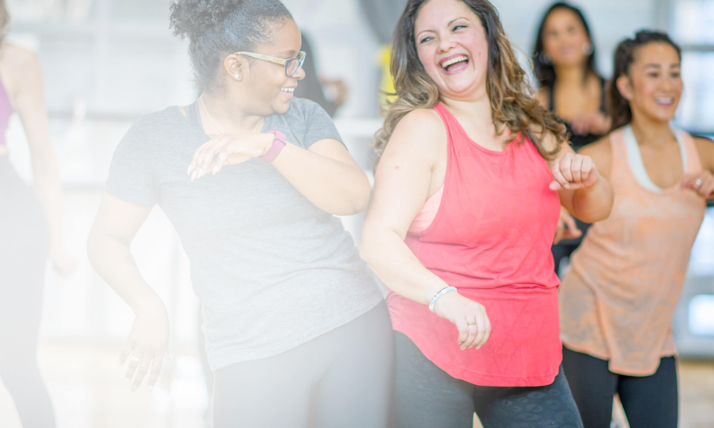 Frauen im Sportoutfit tanzen in einer Gruppe und lachen