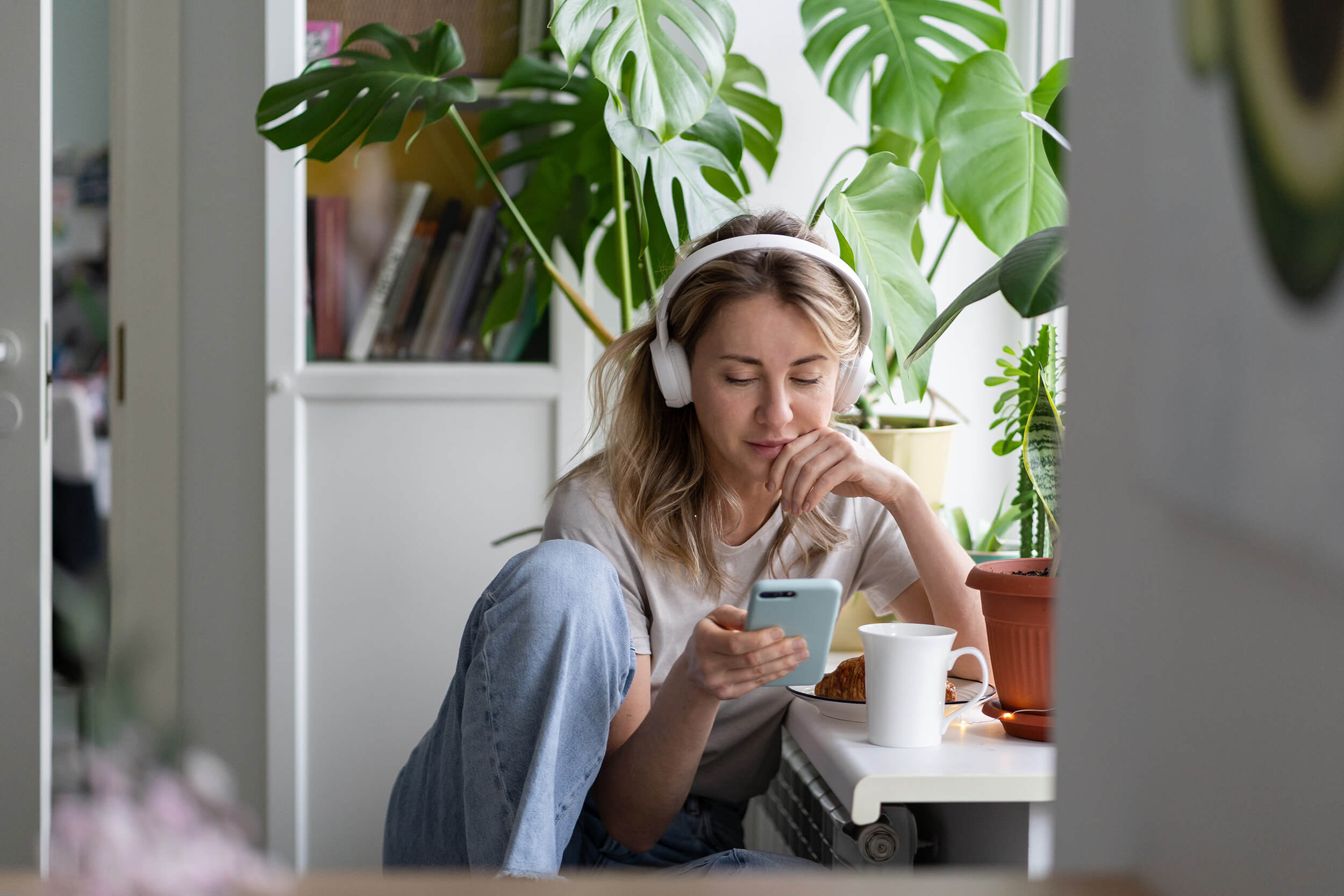 Junge Frau mit Over-Ear-Kopfhörern und Handy in der Hand