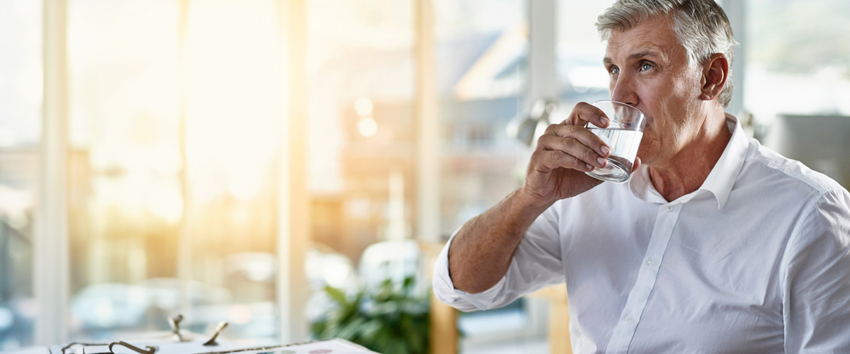hombre con diabetes bebiendo un vaso de agua para regular los efectos del calor