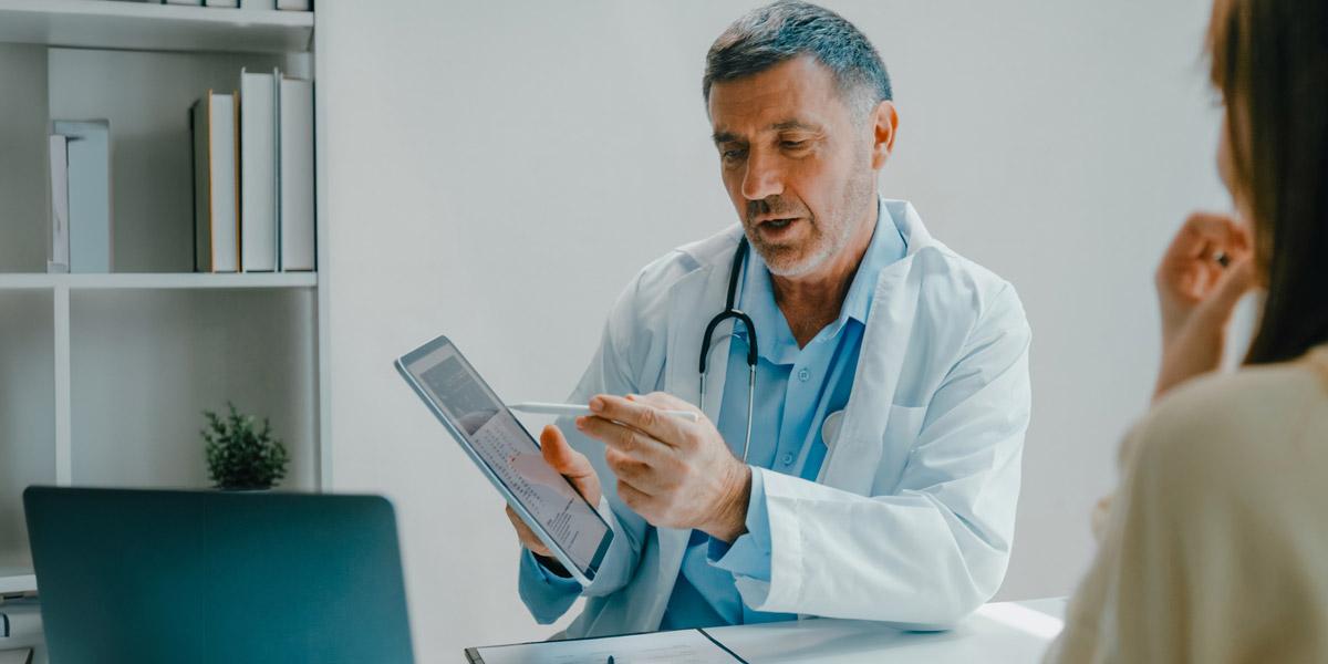 médico enseñandole a su paciente una tablet con sus objetivos en cuanto a control de la diebetes