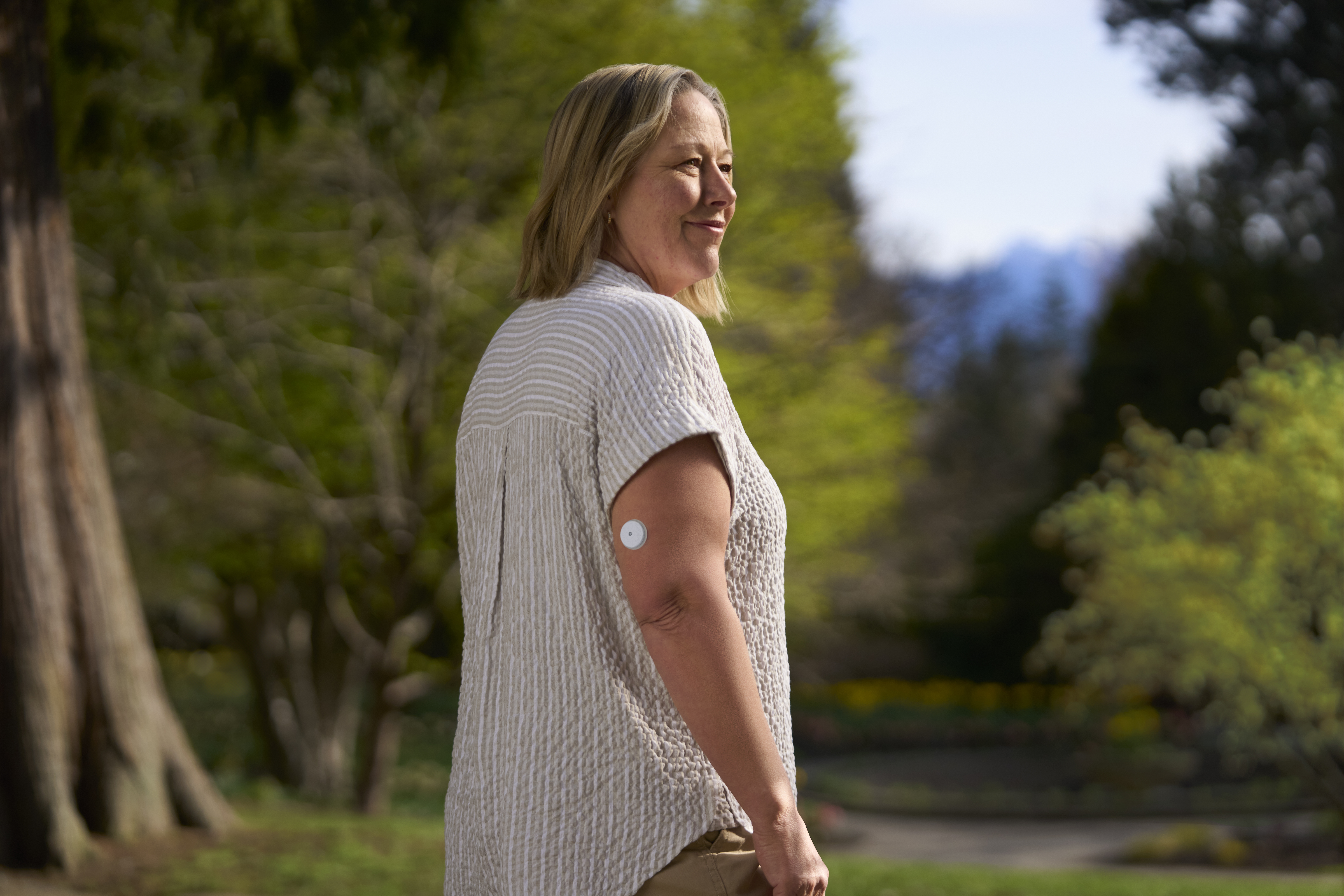 Μια ξαθιά κυρία που φοράει αισθητήρα και χαμογελάει.