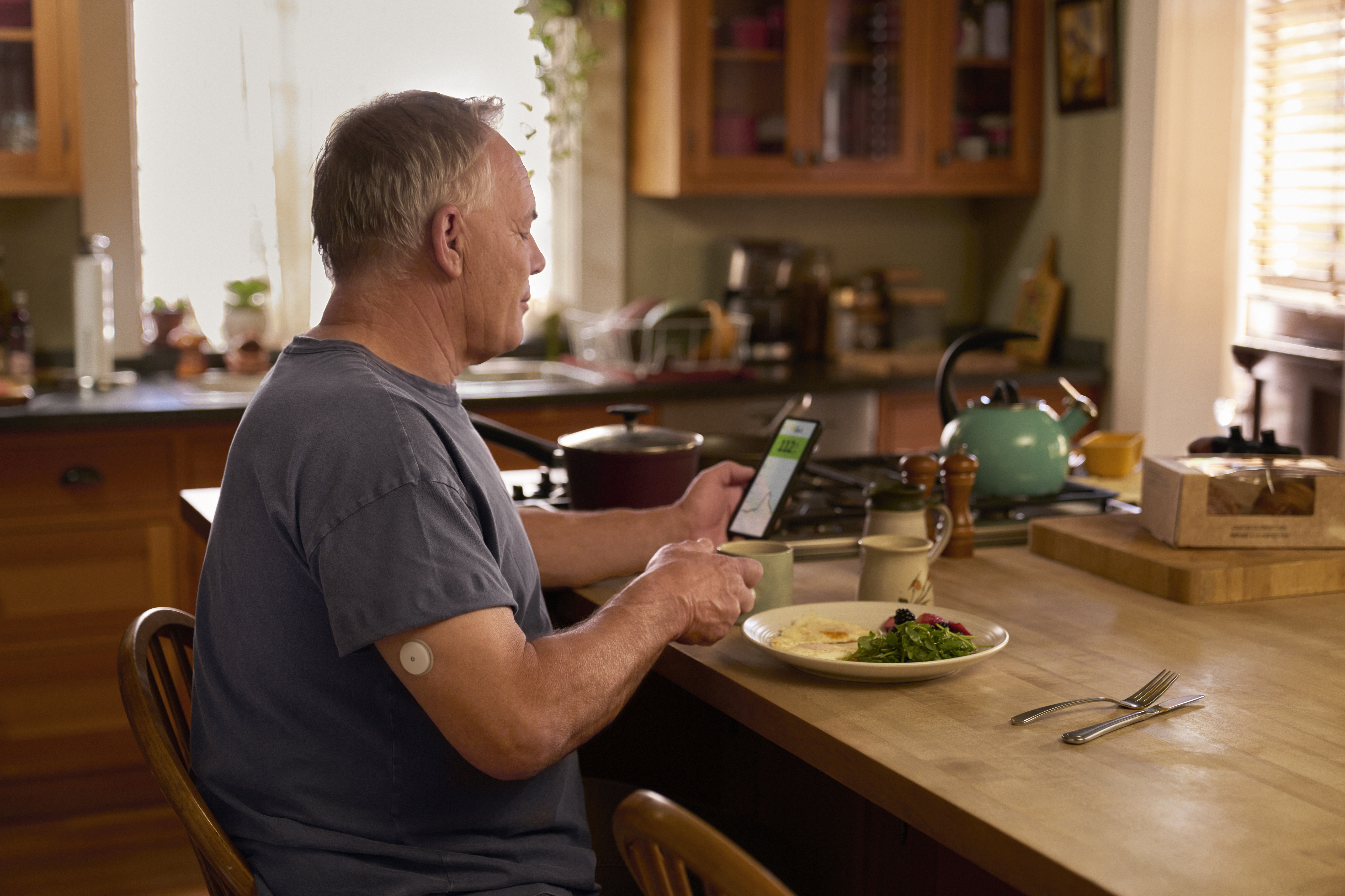 Άνδρας κοιτάζει την εφαρμογή FreeStyle LibreLink στο κινητό του ενώ τρώει