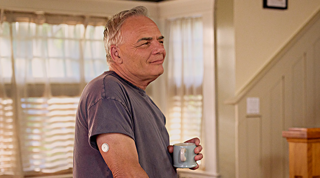 Man wearing FreeStyle Libre 3 Plus sensor in kitchen