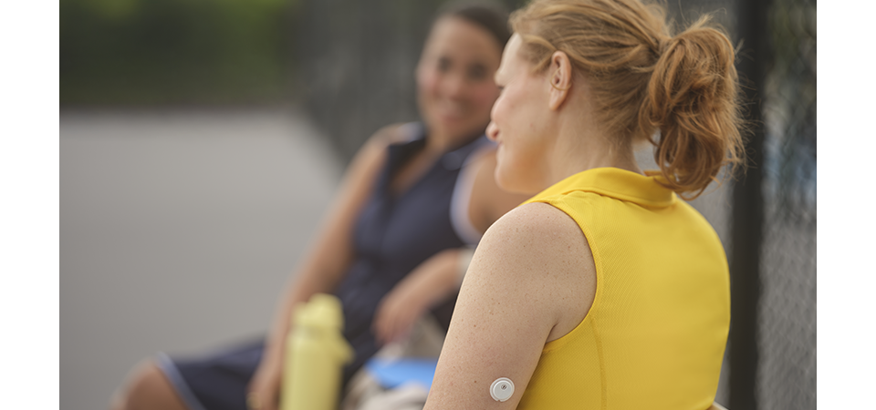 Woman with FreeStyle Libre 2 Plus sensor sitting with friends