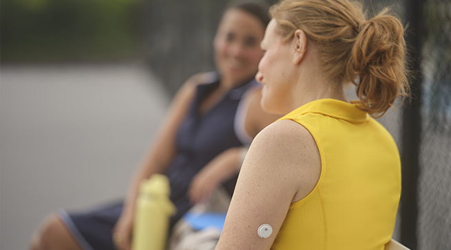 Woman with FreeStyle Libre 2 Plus sensor sitting with friends
