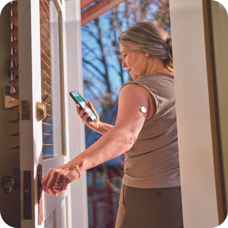 Donna indossa sensore FreeStyle Libre 2 Plus e controlla sullo smartphone l'app Libre