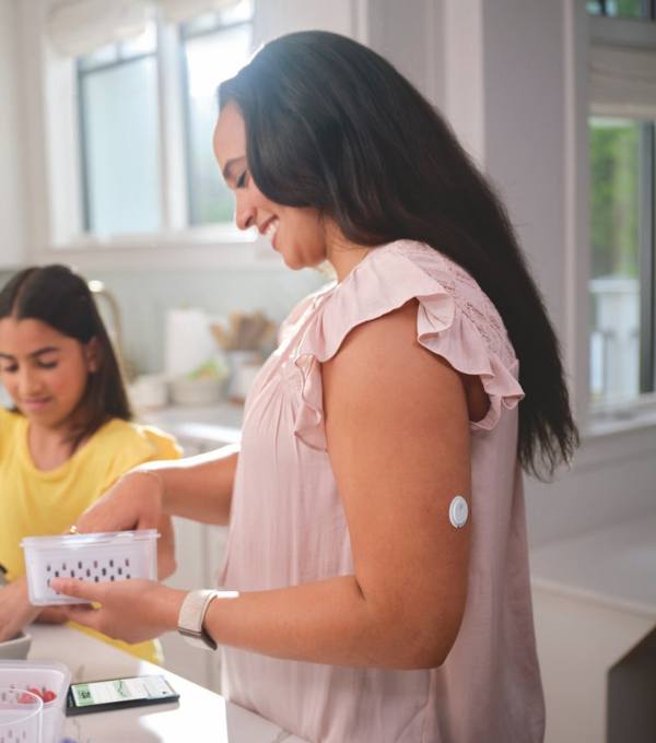 Donna al tavolo di casa indossa il sensore FreeStyle Libre