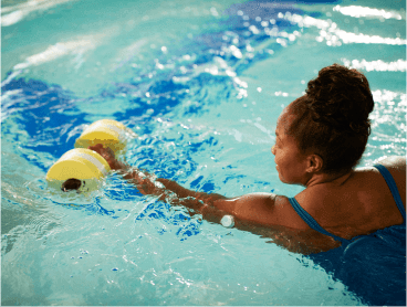 A woman wearing a glucose sensor exercising in a swimming pool.