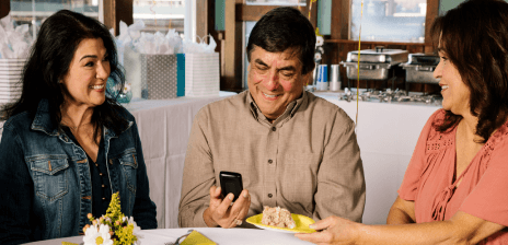 Man enjoying a meal with friends checking his blood glucose on his handheld reader.