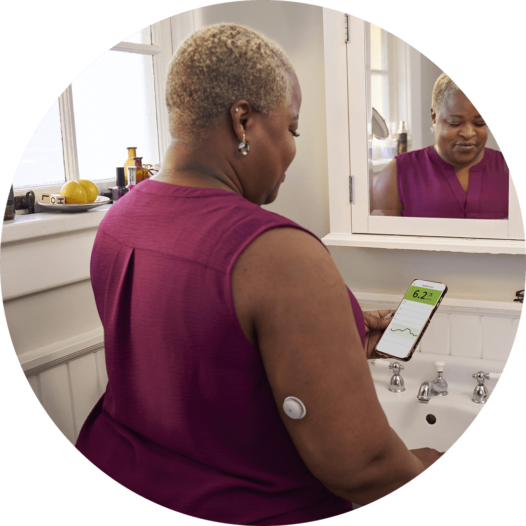 Woman wearing a Libre 2 Plus sensor reviewing her data in LibreLink