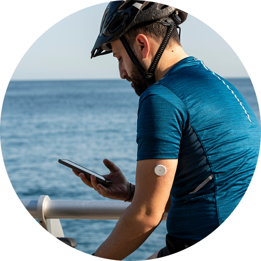 man looking at glucose data on his phone with a visible sensor on his arm