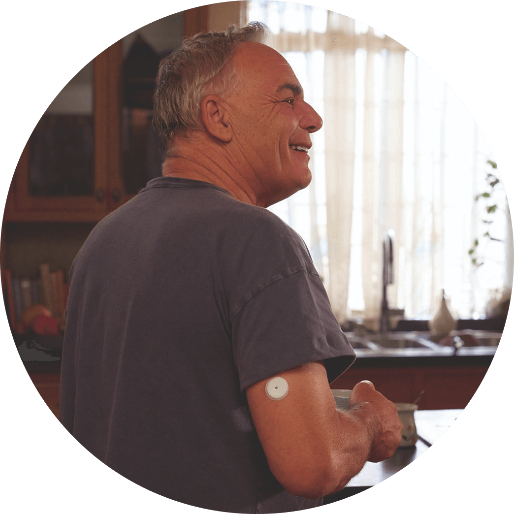 Man in the kitchen smiling with sensor on his upper arm