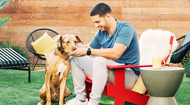 Man with FreeStyle Libre 3 sensor petting his dog