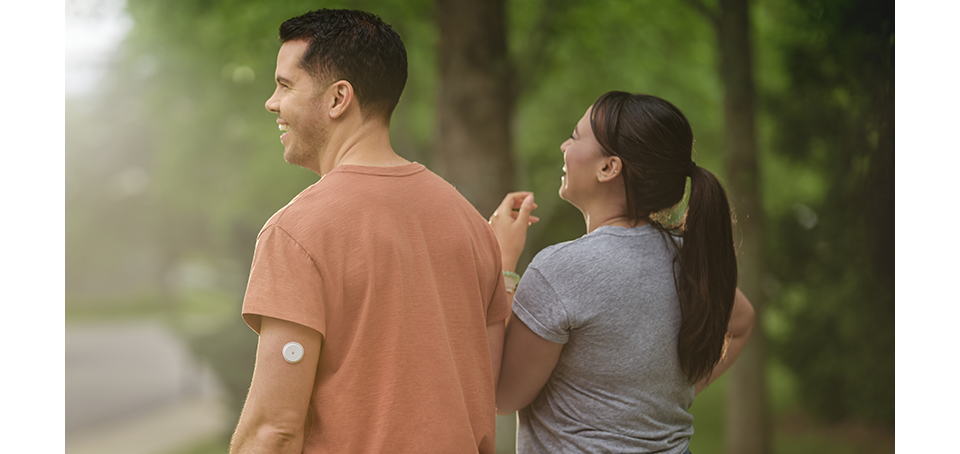 Man wearing Libre 2 Plus sensor walking in a garden with a friend