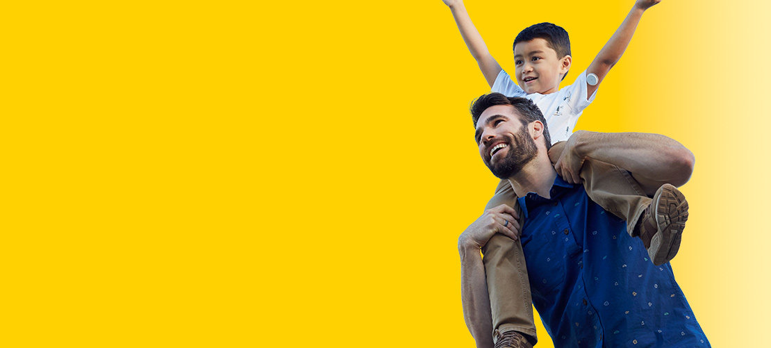 Man with boy on his shoulders. The boy has a Libre 2 sensor on his arm