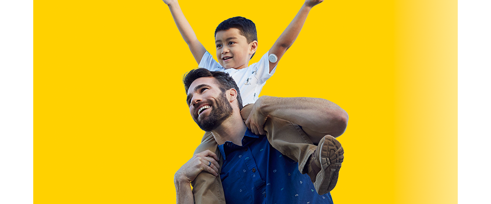 Man with boy on his shoulders. The boy has a Libre 2 sensor on his arm
