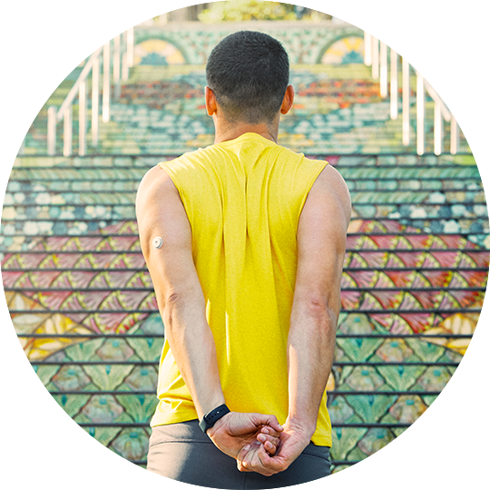 Quelqu'un portant un capteur FreeStyle Libre à l'arrière du bras et tenant une pompe à insuline avec une image en médaillon du capteur et de l'application FreeStyle Libre mis à jour.