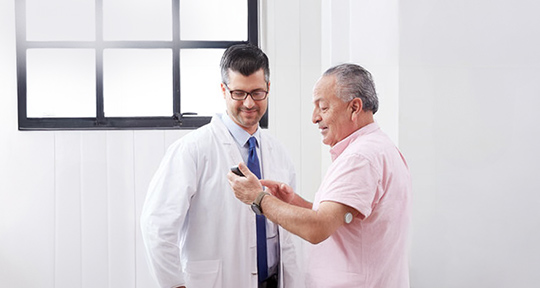 An image of a patient wearing a sensor meeting with his doctor. 