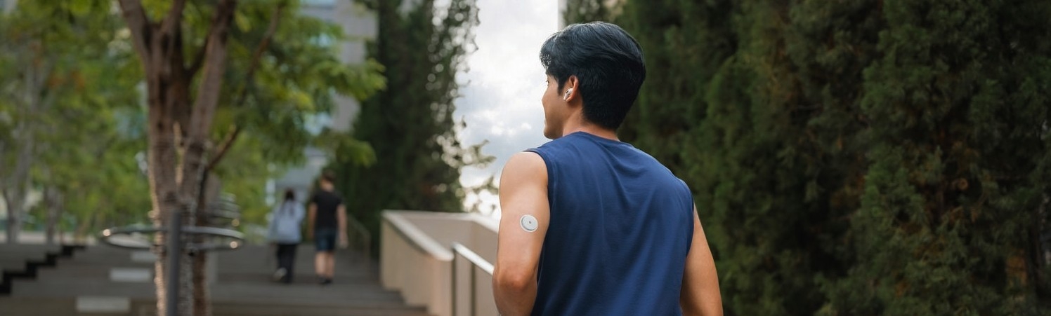 Profissional de saúde mostra dados no celular a paciente que utiliza o sensor FreeStyle Libre 2 Plus no braço durante consulta.