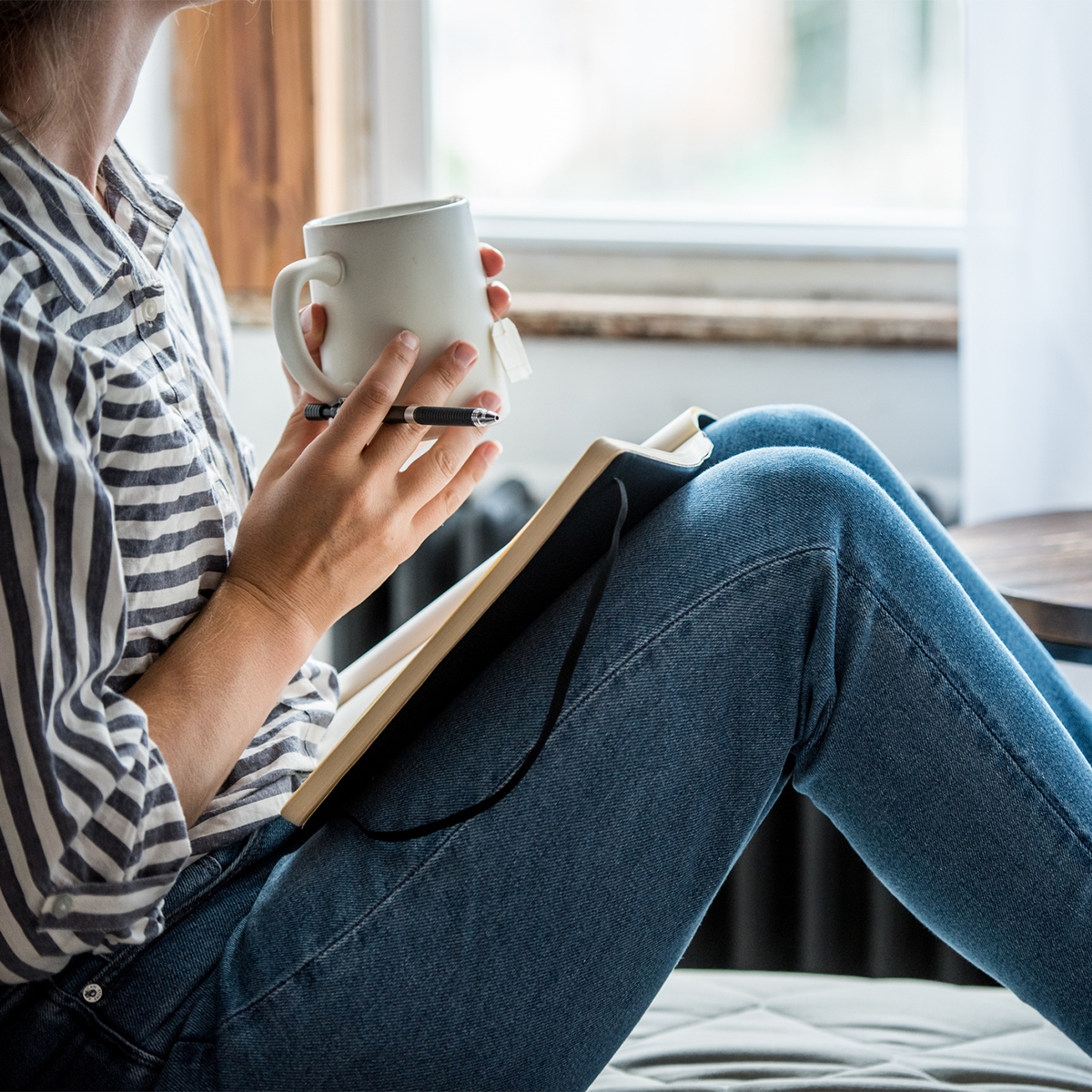Sitzende Frau mit Kaffeetasse und Heft 
