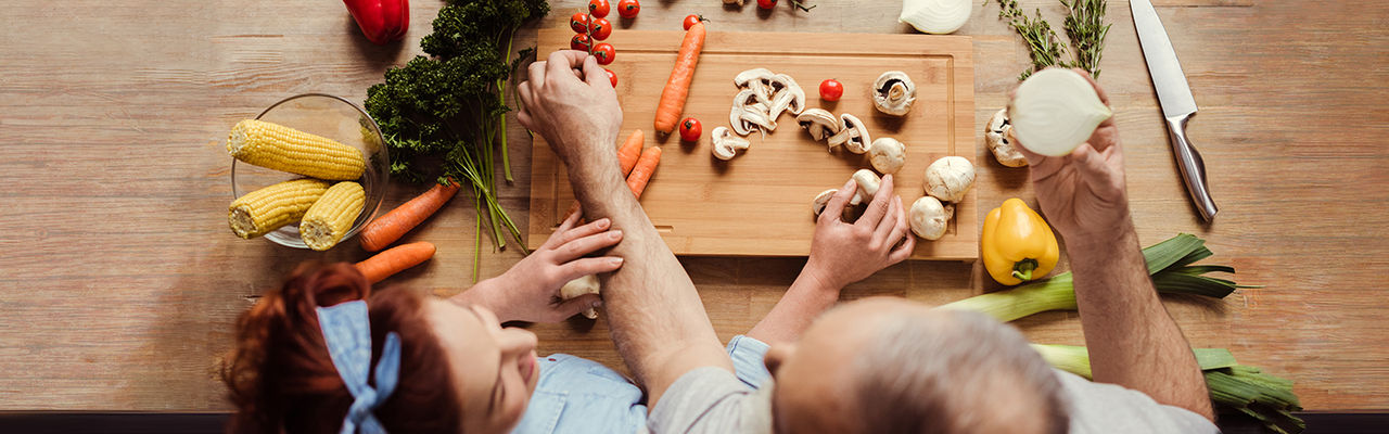 Overhead view of mature couple at kitchen table preparing vegan food