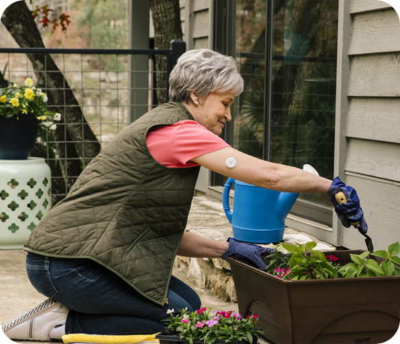 Kvinde laver havearbejde med FreeStyle Libre 2 sensoren på bagsiden af overarmen