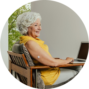 Smiling woman working at a computer while wearing a FreeStyle Libre sensor